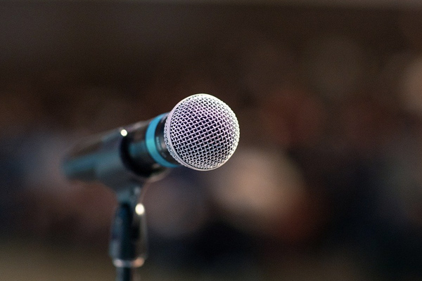 closeup of vocal microphone in foreground against blurred background