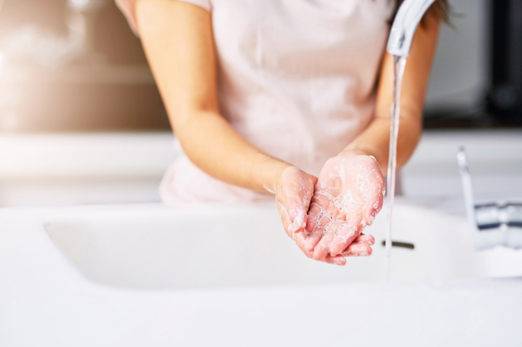 Medical staffer washing hands at sink