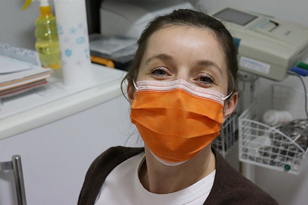 smiling woman wearing breathing mask in medical environment