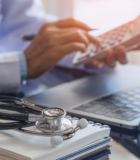 Healthcare - medical professional typing on handhelp device; stethoscope in foreground