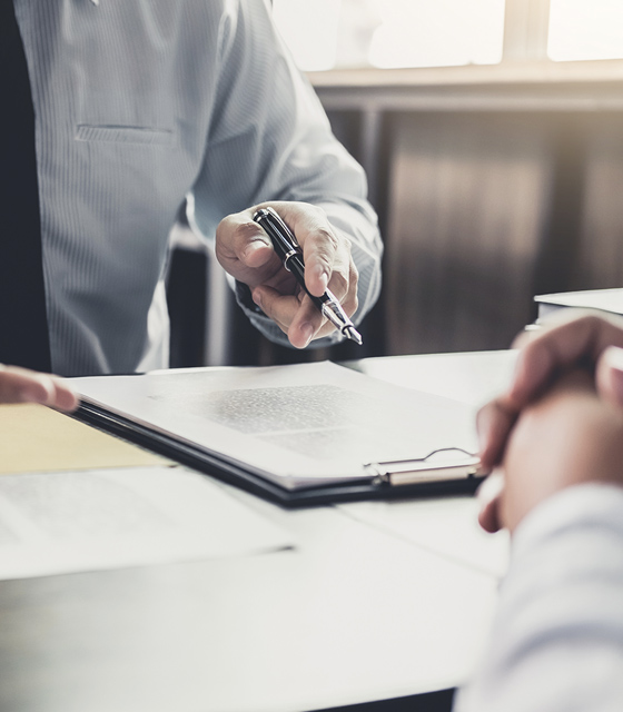 Labor and Employment - businessperson with pen gesturing over contract documents