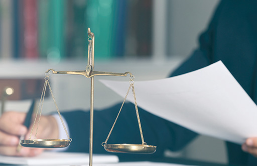 scale of justice statuette in foreground; person reviewing document in background