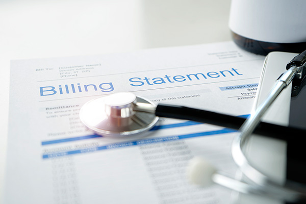 billing statement document with stethoscope resting on page alongside an iPhone