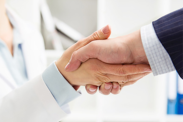 medical professional shaking hands with businessperson