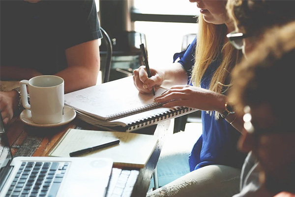 people around a table working out numbers on a writing pad.