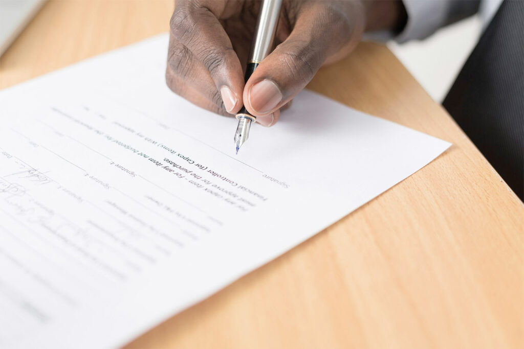 Professional person signing a legal document with a fountain pen.